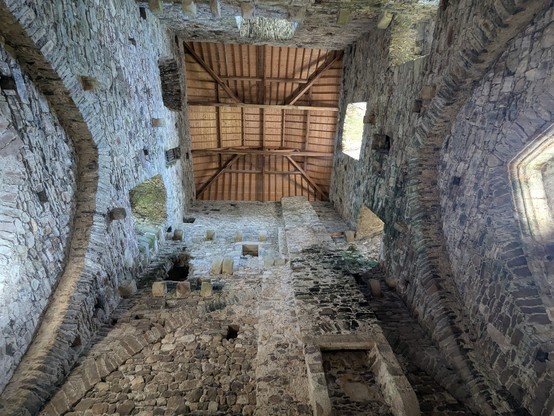Looking up the tower of Tintern Abbey, a medieval monastery. 
The roof is modern (wood) and the building has been heavily altered - it was turned into a stately home, which explains the fireplace.
Nevertheless, you can see the outlines of the arches which led into the nave and chancel, and the original floor supports. 
Various doorways (now leading to thin air) are also visible 