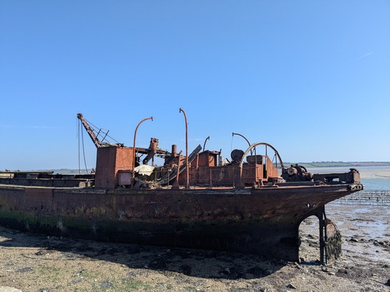 A shipwreck on a beach - a rusting hulk with an intact hull, but missing propeller. 
This is the Port Lairge (Waterford) which was a dredger, for the city of the same name. 
It was used up until the late 80s, apparently. 