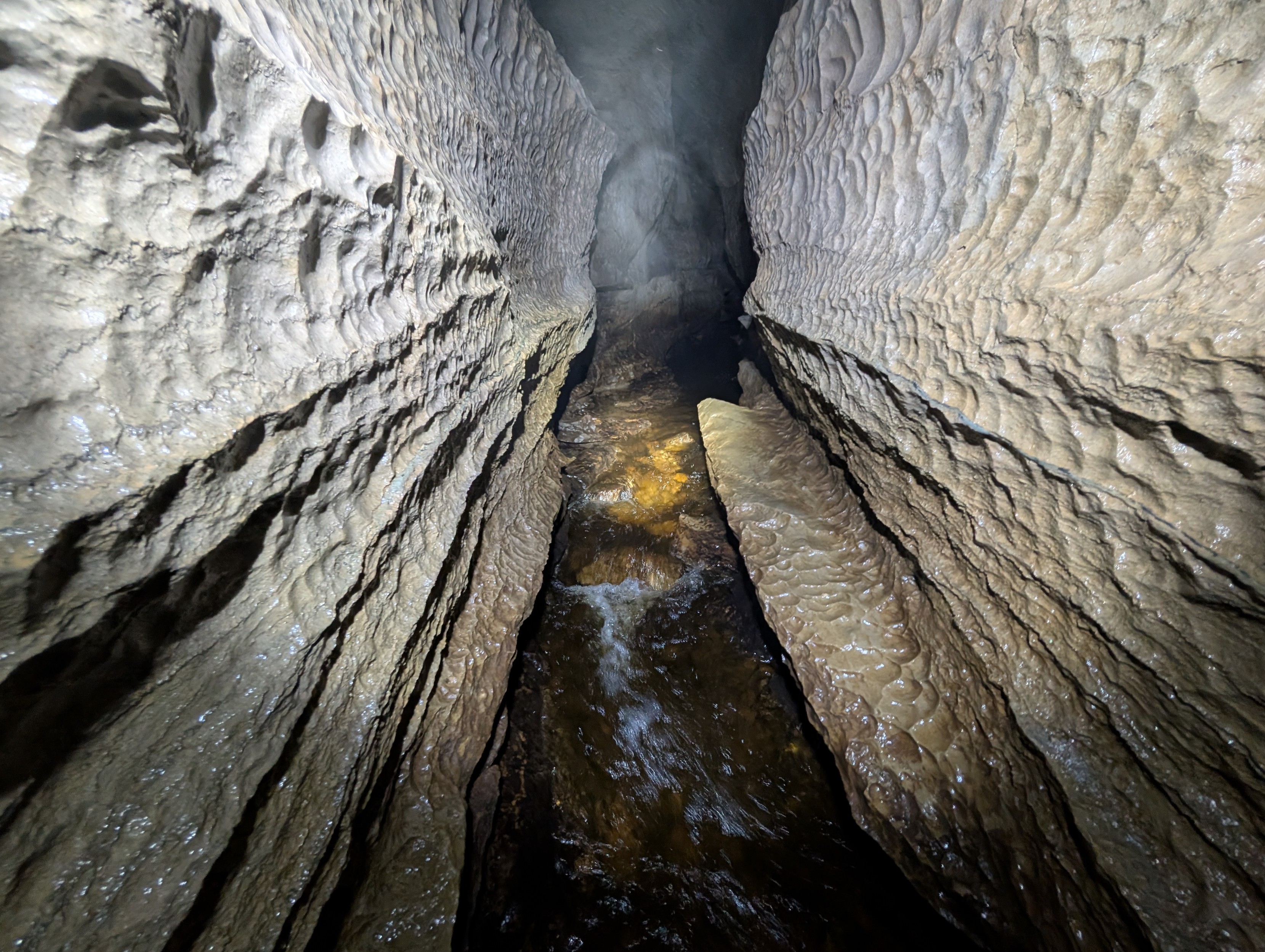 A rift in a cave. The streamway is at the bottom, and you can see where the layers of rock have been eroded by running water over milenia